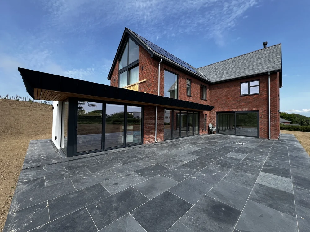 Brick new build with anthracite windows and slate patio