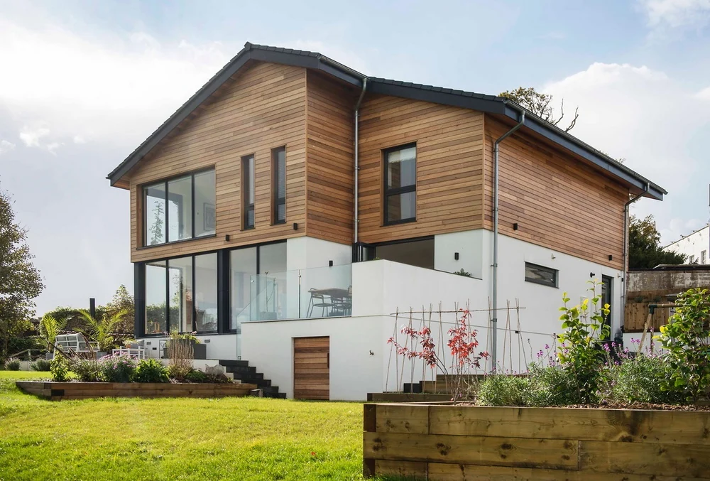White render, cedar cladding, anthracite windows and zinc gutters